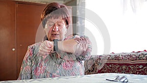 An elderly woman checks the messages on a smart watch. She reads reminders and speaks the phrase for a search. After