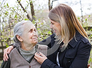 Elderly woman with cheerful caregiver outdoor, springtime