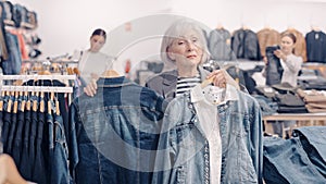 Elderly woman choosing denim jacket in store