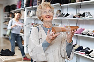 Elderly woman choosing moccasins in shoeshop