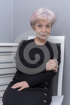 An elderly woman clutches a metal brass knuckles while sitting on a chair in the room. Concept, women`s self-defense, traumatic ob