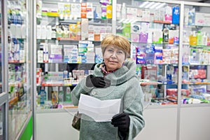 Elderly woman in   coat buys medicines at   pharmacy