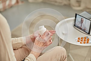 An elderly woman communicates remotely via a tablet with her doctor and takes medications according to his recommendations.