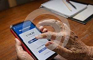 Elderly woman confused and  trying to pay bill on cellphone