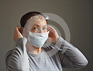 An elderly woman, during the coronavirus pandemic, wears a protective medical mask. Flu epidemic, dust allergy, protection from