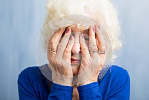 Elderly woman covering her face with both hands