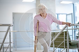 Elderly woman with a crutch walking upstairs