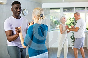 Elderly woman dancing merengue with african american partner