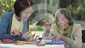 Elderly woman and daughter in the needle crafts occupational therapy for Alzheimerâ€™s or dementia