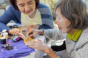 Elderly woman and daughter in the needle crafts occupational therapy for Alzheimerâ€™s or dementia