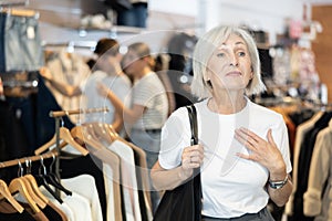 Elderly woman delicately examines garments