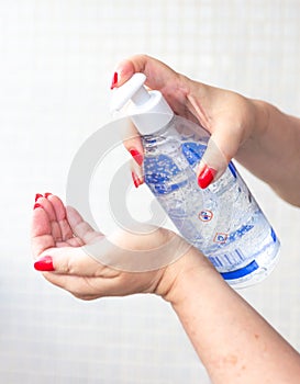 Elderly woman disinfecting her hands with alcohol gel to prevent contamination by the corona virus