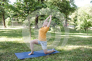an elderly woman does yoga in the park to perform stretching for balance and balance.