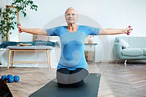 elderly woman doing an exercise with dumbbells with an online trainer.