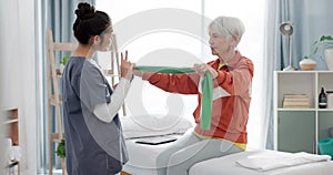 Elderly woman doing exercise with a resistance band for physical therapy with nurse in clinic. Fitness, healthcare and