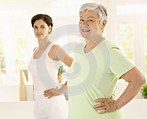 Elderly woman doing exercises with trainer