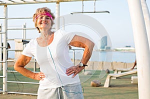 Elderly woman doing gymnastic exercises on the sportsground on beach