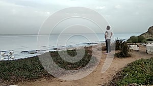 Elderly woman doing physical exercises on a high seashore