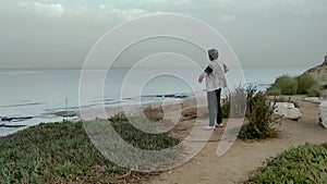 Elderly woman doing physical exercises on a high seashore