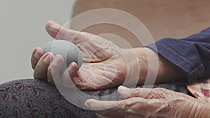 Elderly woman doing rubber ball for exercise fingers, palm ,hand and foot muscle with caregiver take care