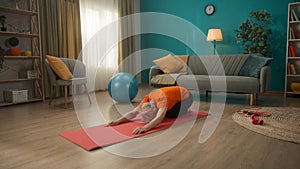 Elderly woman doing stretching after a workout. A gray-haired woman sitting on her knees pulls her pelvis back and