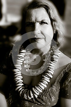 An elderly woman dressed in the old Russian style with a samovar, a bright headscarf on her shoulders and a bunch of bagels