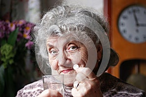 Elderly woman drinks a medicine pill