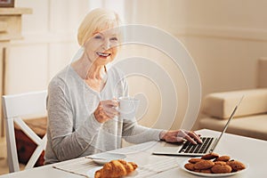 Elderly woman eating biscuits while typing business letter