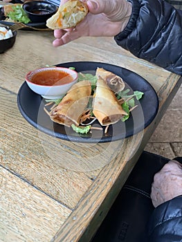 Elderly woman eating  patties rolls of dough stuffed with meat. Japanese or Chinese appetizer