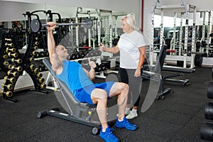 An elderly woman, eldest is engaged in sports in gym. Muscles swing barbell. Retired concept, healthy lifestyle, indoor