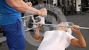 elderly woman, eldest is engaged in sports in gym. Muscles swing barbell. Retired concept, healthy lifestyle, indoor