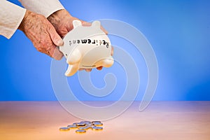 Elderly woman empties her piggybank with savings retirement photo