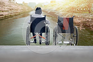 Elderly woman with empty wheelchair together