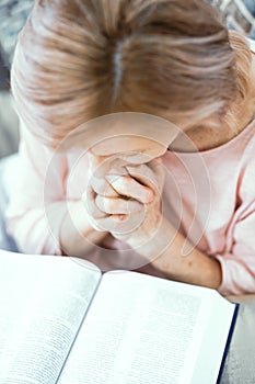 An Elderly Woman of European Appearance Prays Near the Bible.