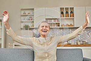 An elderly woman experiences the joy of being at home with her arms wide open. Happy pensioner concept