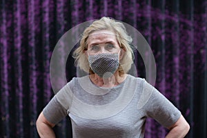 Elderly woman in face mask portrait outdoor. Old aged female wearing protective medical mask.