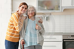 Elderly woman with female caregiver in kitchen.