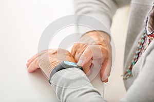 Elderly woman with fitness band checking her pulse, closeup