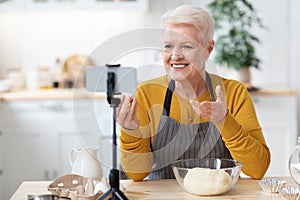 Elderly woman food blogger recording her cooking on smartphone