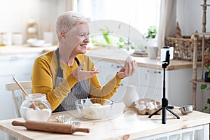 Elderly woman food blogger recording her cooking on smartphone