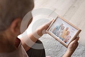 Elderly woman with framed family portrait