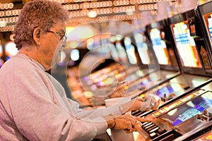 Elderly woman gambling on slot machine