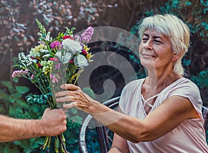 Elderly woman get a beautiful bouquet of field flowers.