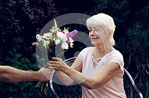 Elderly woman get a beautiful bouquet of field flowers.