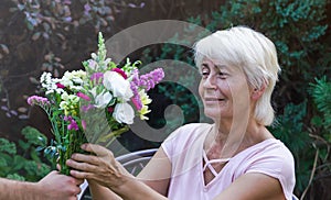 Elderly woman get a beautiful bouquet of field flowers.