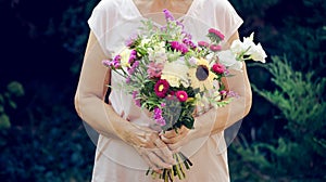 Elderly woman get a beautiful bouquet of field flowers. Senior lady holding a bunch of flowers.