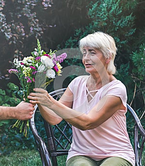 Elderly woman get a beautiful bouquet of field flowers.