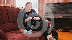 Elderly woman in glasses begins to knit