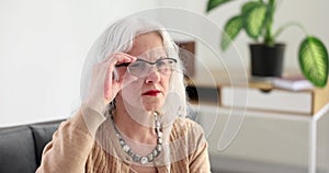 Elderly woman with gray hair adjusting eyeglasses at home 4k movie slow motion