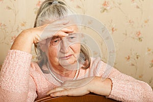 Elderly woman grieves at home.